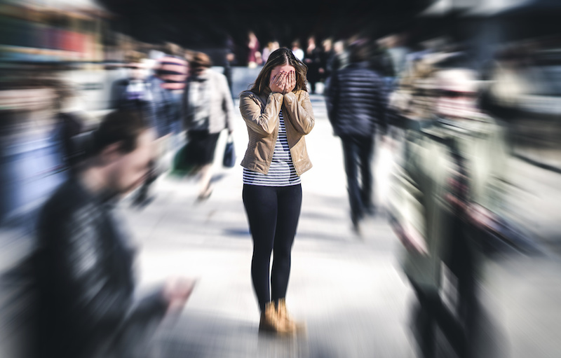 Young adult overwhelmed by anxiety in a crowd, frozen and uncertain