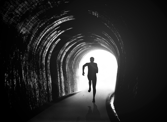 Young adult walking toward light through tunnel, symbolizing growth after feeling stuck.